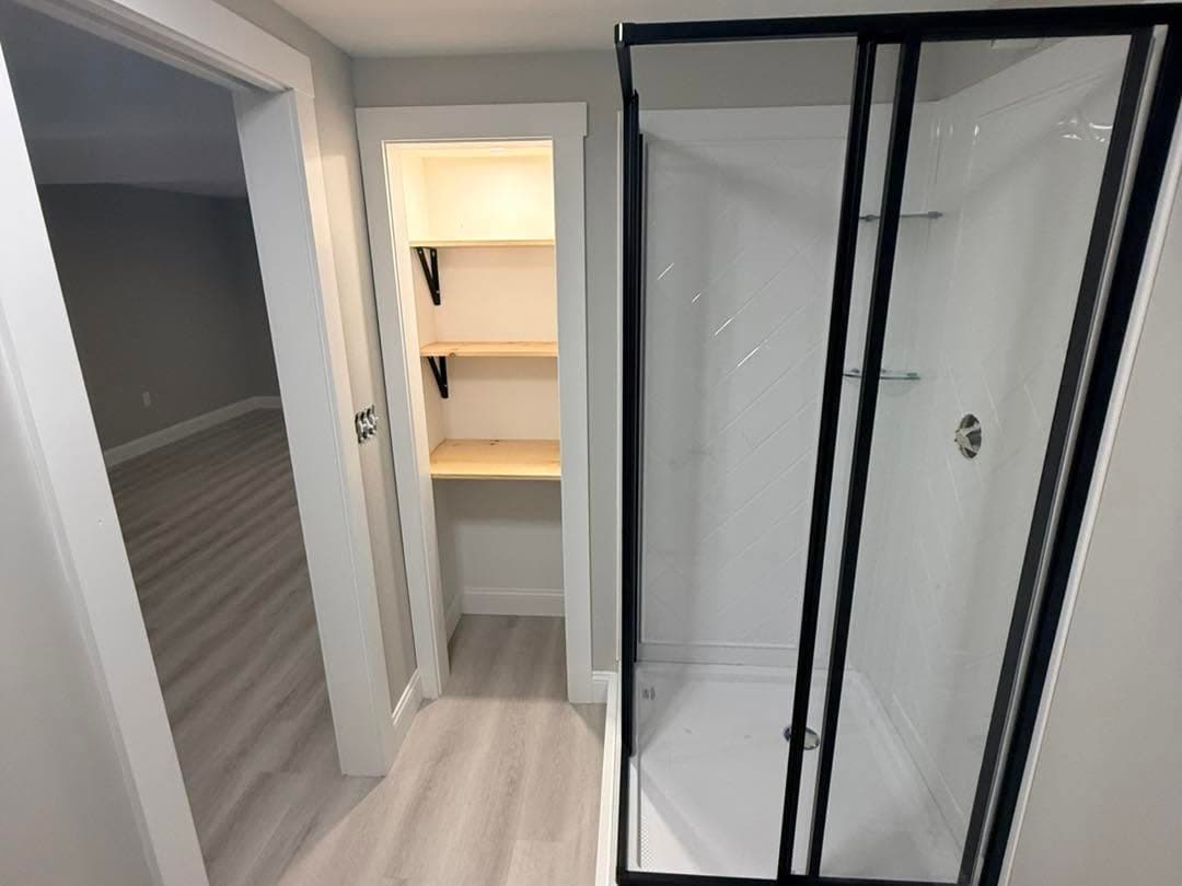 Finished basement hallway with glass shower door