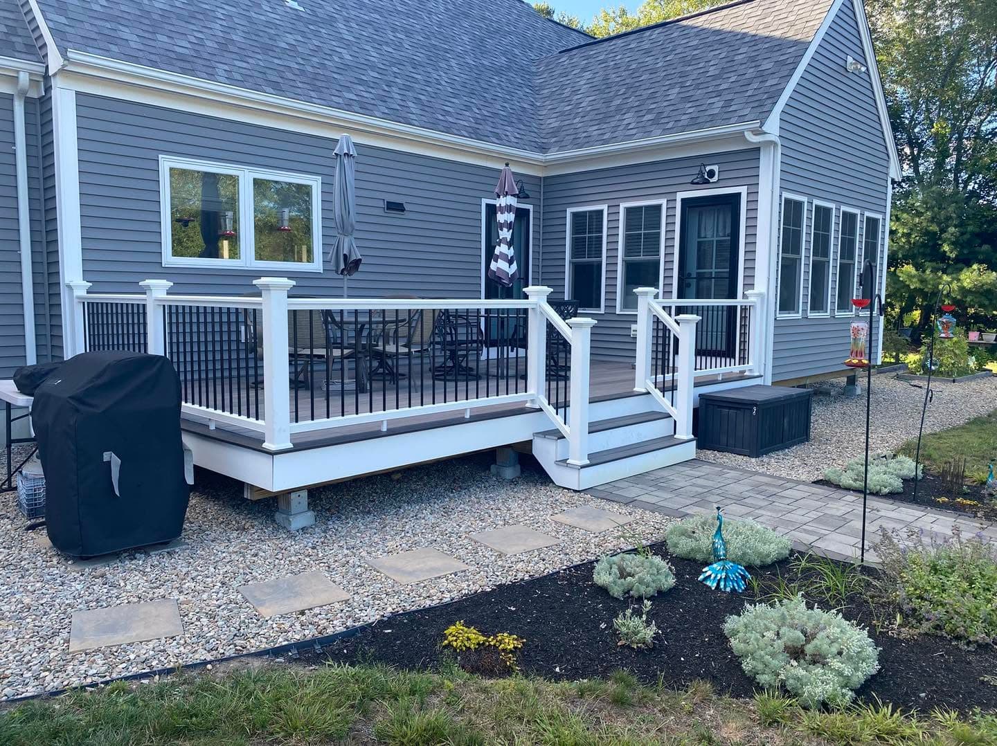 Gray home exterior with white deck and landscaping