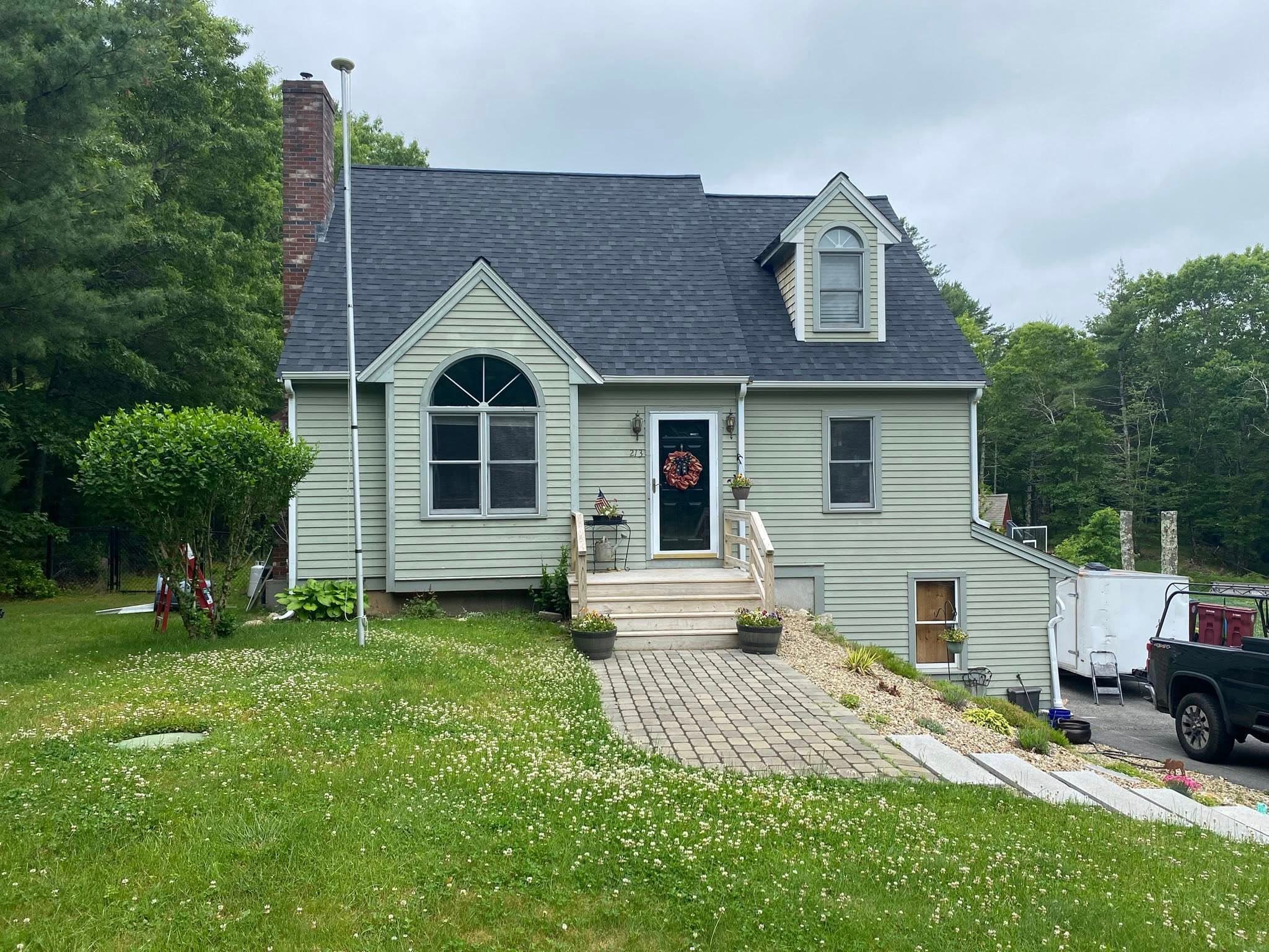 Sage-green Cape home with paver walkway and landscaping