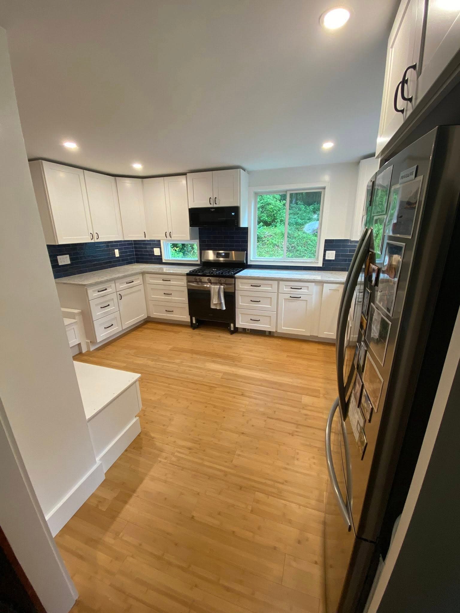 Remodeled kitchen with white cabinets and wood flooring