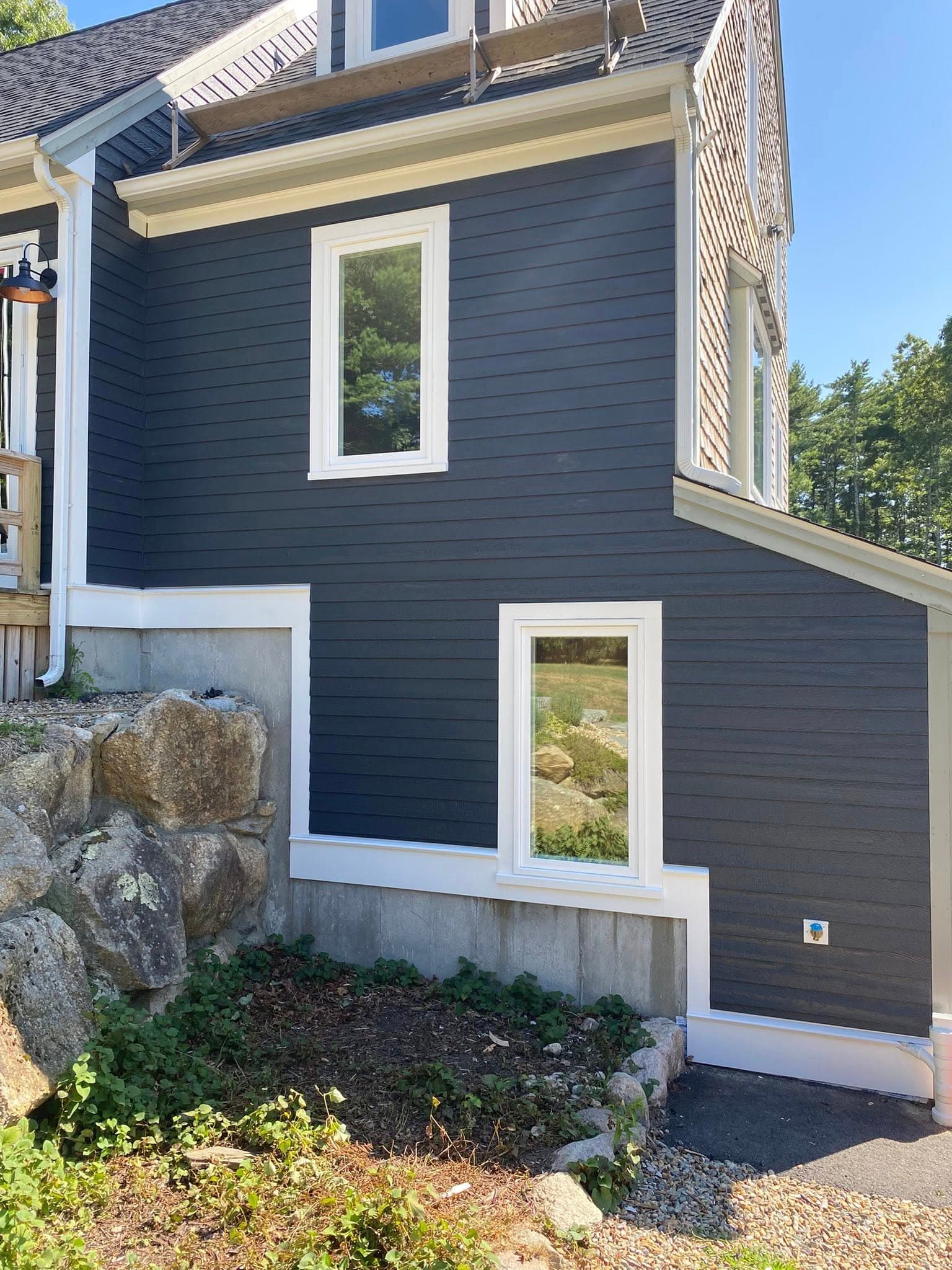 Corner detail of navy siding meeting stone veneer with white trim