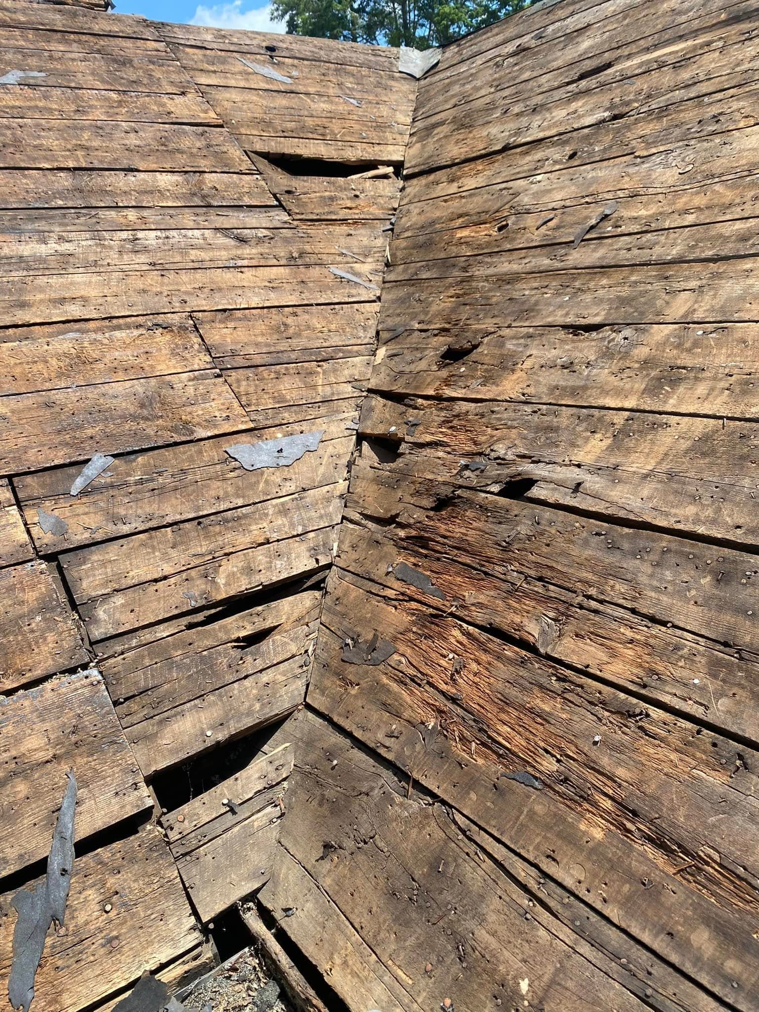 Rotted roof decking boards exposed after shingle tear-off
