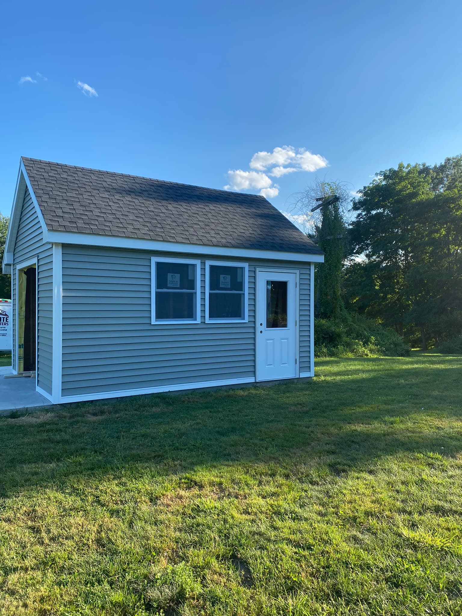Finished shed with gray vinyl siding and windows